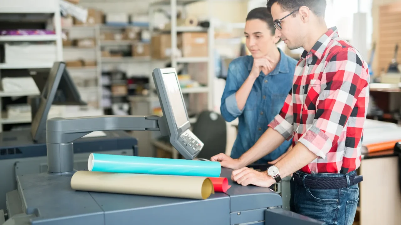 Techniciens étudiant un plan de découpe et un développé à plat dans un atelier de packaging