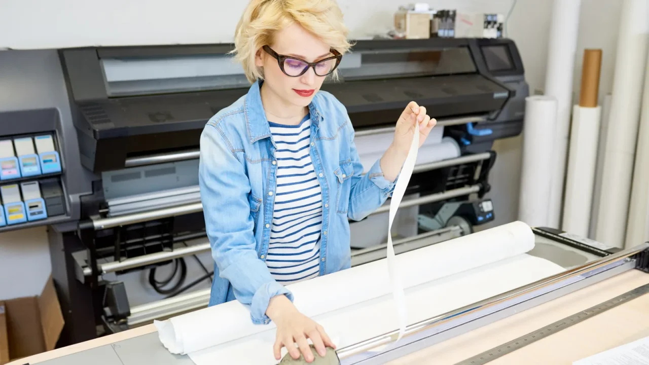 Opératrice préparant un support papier en rouleau avant impression dans un atelier