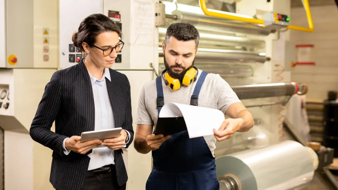Responsable de production et opérateur consultant un dossier de fabrication dans un atelier d'emballage