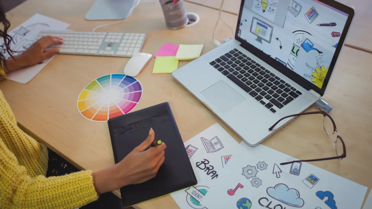 Graphiste esquissant un projet de création entre tablette graphique et ordinateur portable