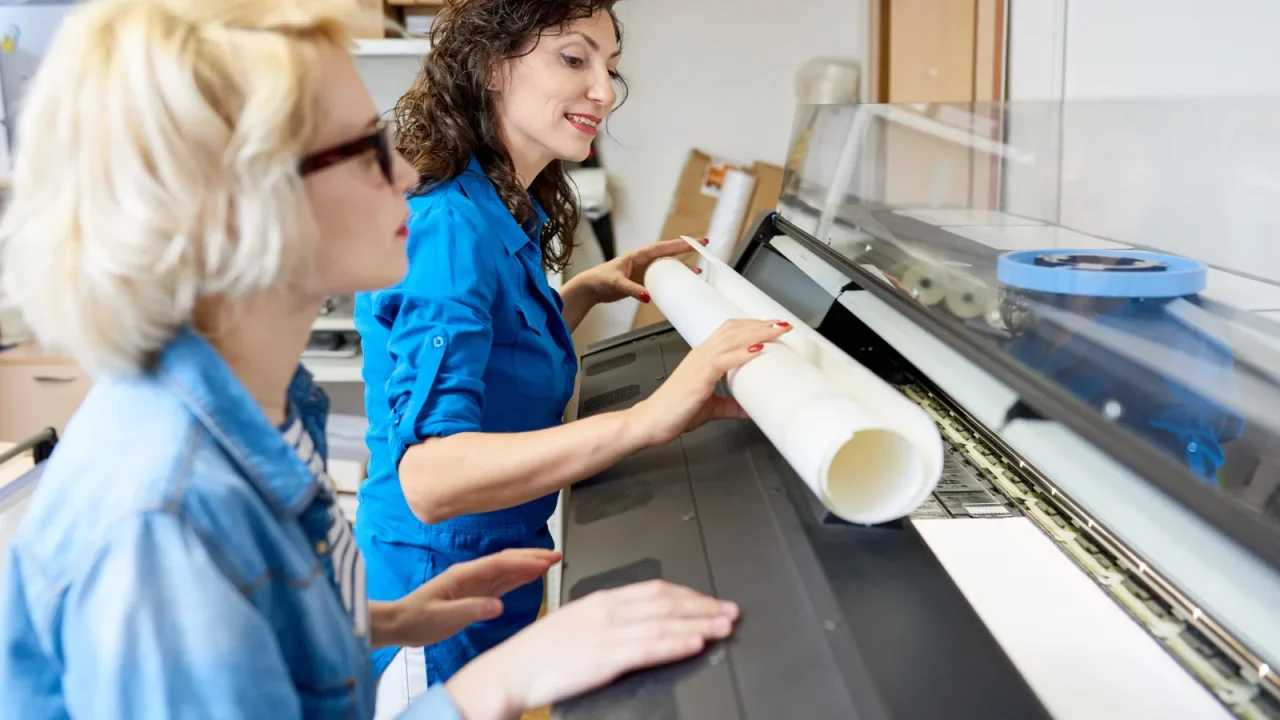 Deux reprographes préparant un tirage sur une machine de production grand format