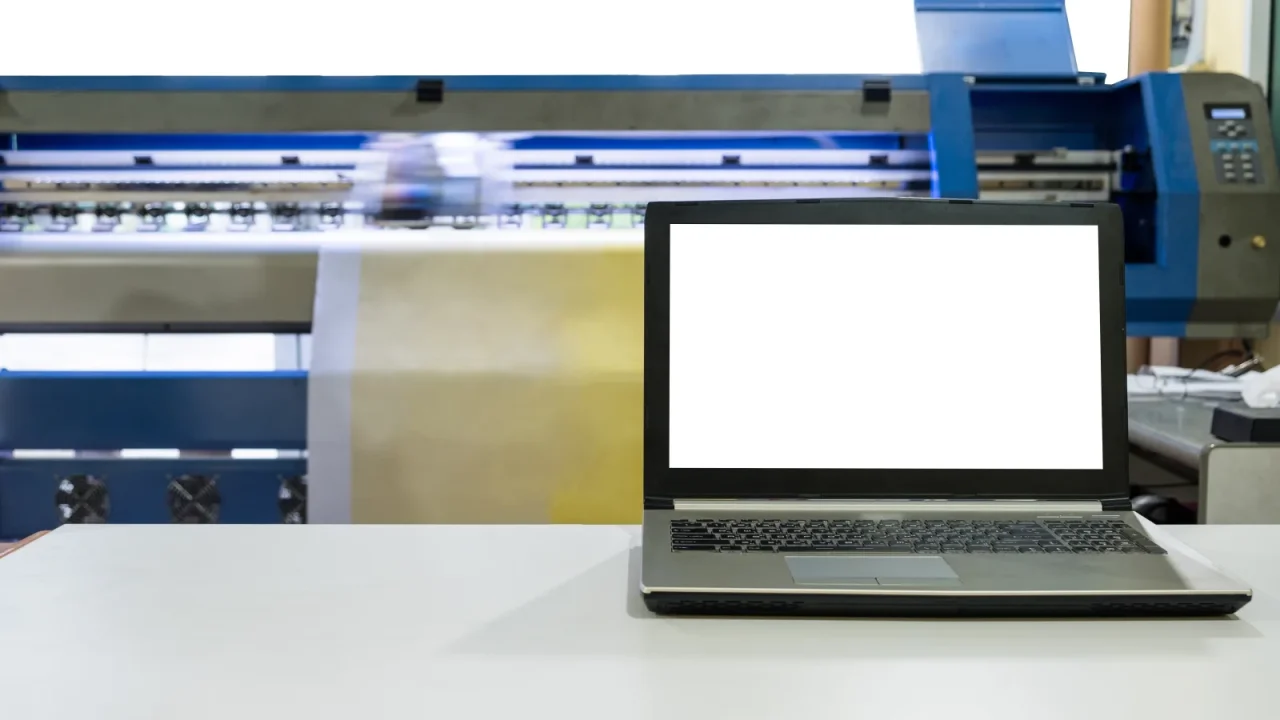 Ordinateur portable posé près d'une imprimante professionnelle dans un atelier