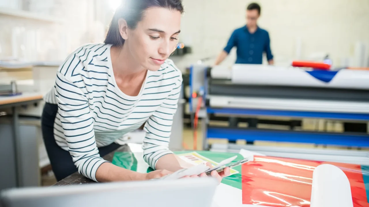 Imprimeuse travaillant sur son logiciel de gestion en ligne depuis un ordinateur portable en atelier